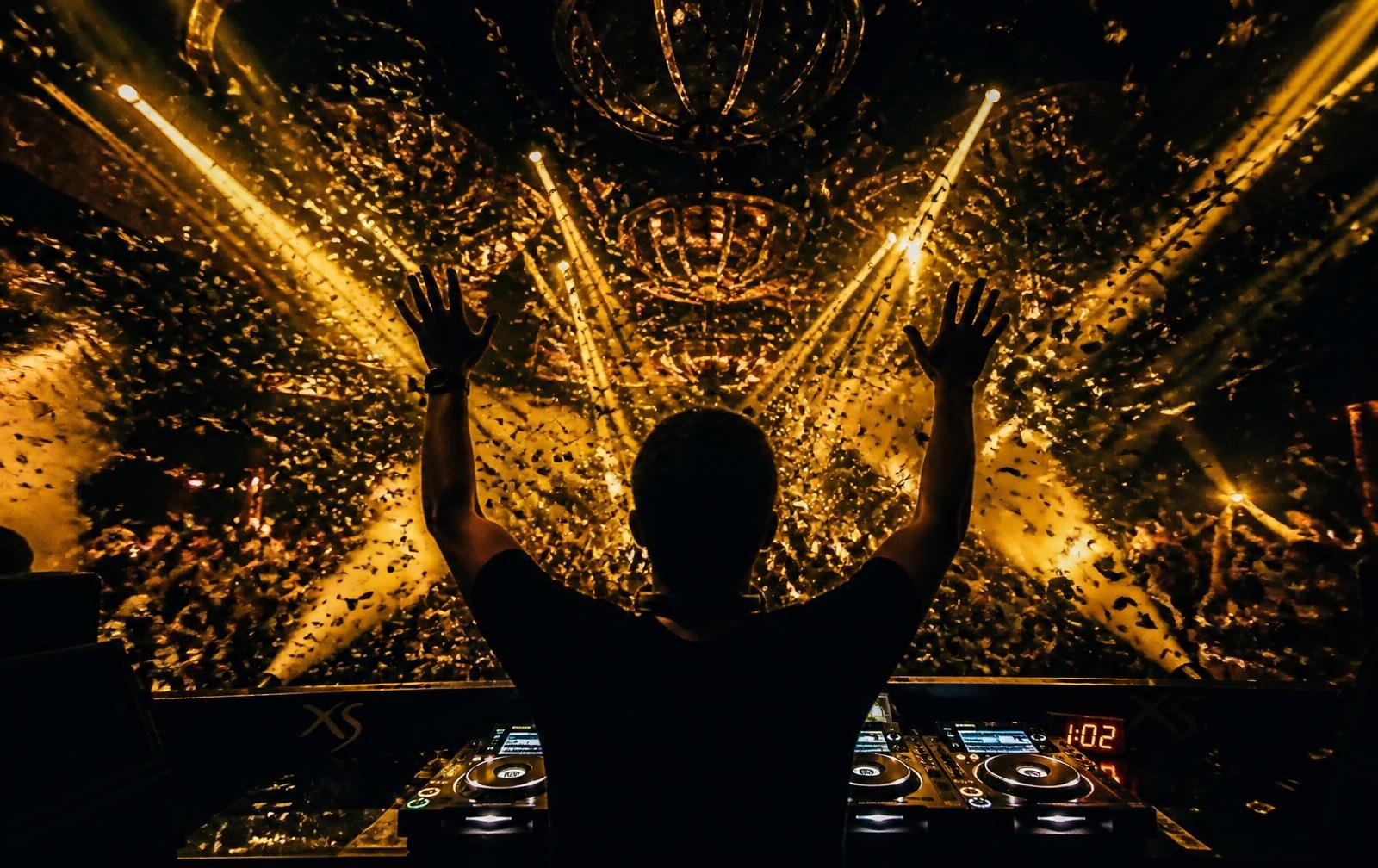 DJ silhouette hands up under confetti